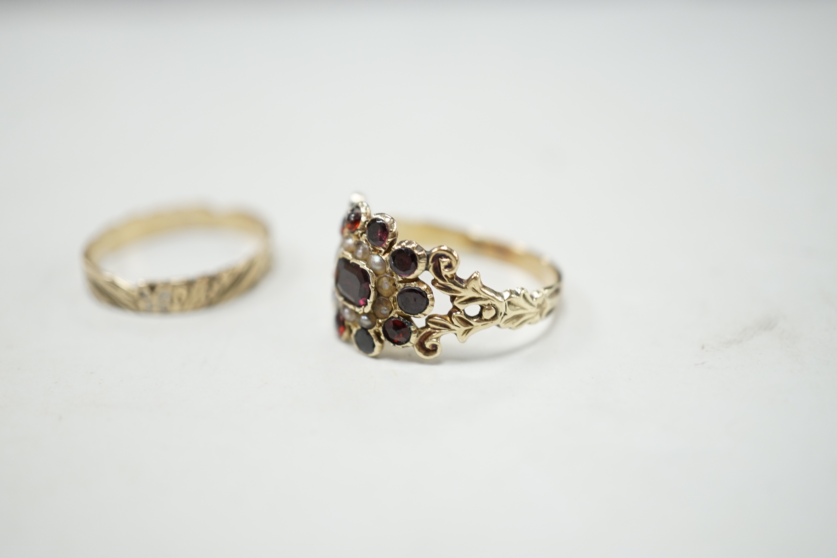 An early 19th century yellow metal, garnet and seed pearl cluster set ring, size P and a 19th century yellow metal and two colour enamel set band.